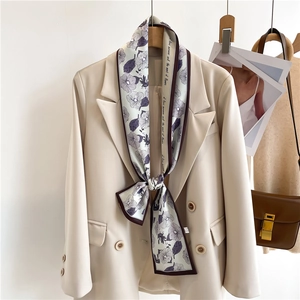 Elegant floral print skinny silk scarf styled on a beige double-breasted blazer lapel