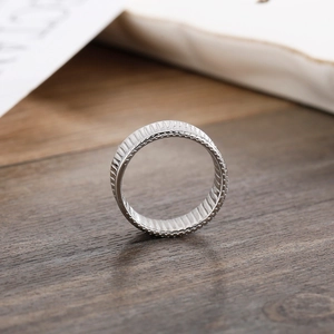 Detail view of silver striped metal ring with grooved texture on a dark wood surface
