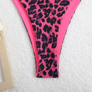 Front view of pink and black leopard print bikini bottom on a white plush rug