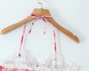 Detail of pink floral halter top with white lace ruffle edges and adjustable neck ties