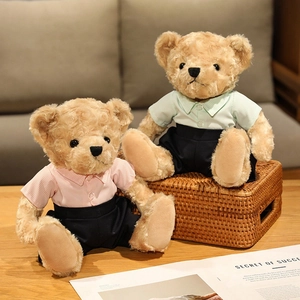 Pair of plush teddy bears in collegiate outfits on a wooden table with soft lighting