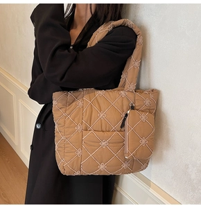 Detailed shot of caramel quilted tote bag featuring floral embroidery and small coin purse