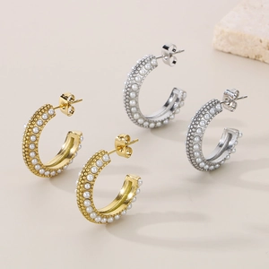Detail view of gold and silver C-shaped stainless steel earrings with pearl insets