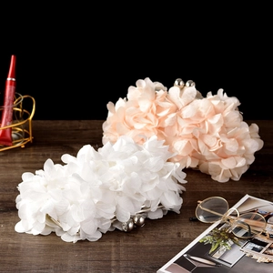 Detail of floral petal clutches in white and cream pink satin on a wooden background