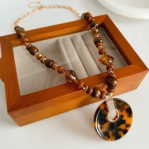 Détail de perles en bois et pendentif léopard écaille de tortue serti de strass