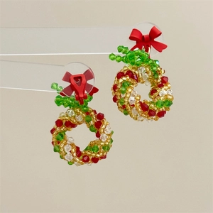 Detailed close-up of beaded Christmas wreath earrings with crystals and a red bow