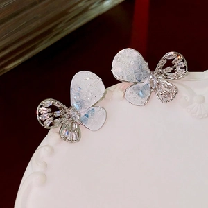 Sparkling butterfly earrings with white translucent wings and crystals on a pedestal