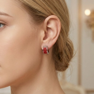 Close-up of a silver-tone C-shaped hoop earring with sparkling red crystals on model