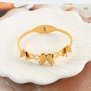 Detail of golden butterfly open bangle with matte butterfly charms and hollow links