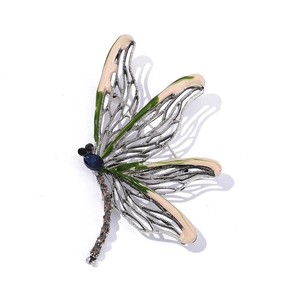 Detailed close-up of a crystal dragonfly brooch with green enamel wings and blue gemstone