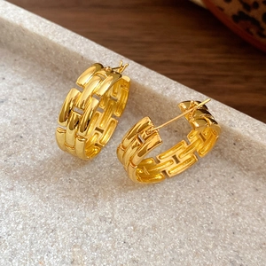 Gold C-shaped earrings with interlocking brick texture and high polish finish