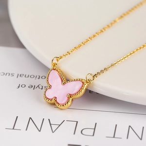 Macro view of golden necklace with pink butterfly pendant featuring delicate beaded edges