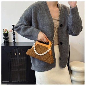 Detailed shot of a brown plush evening bag with a vintage wooden handle and pearl chain