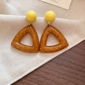 Close-up of vintage resin drop earrings with yellow spheres and amber triangles