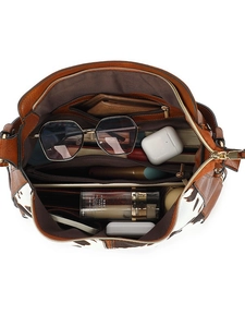 Brown leather cow print tote bag showing spacious interior with multiple compartments