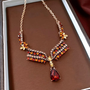 Macro shot of vintage gold necklace with red teardrop crystal and floral rhinestones