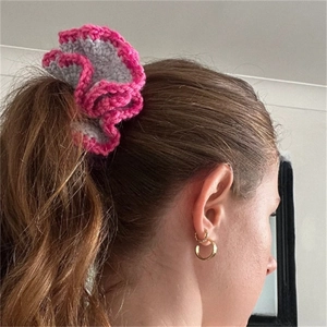 Detail of grey ruffled crochet hair scrunchie with pink edges on model's ponytail