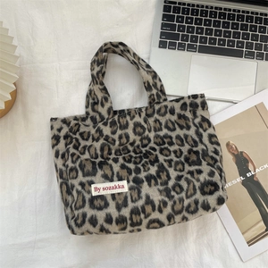 Detailed top view of leopard print plush tote bag with fabric logo tag on white fabric