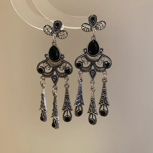 Macro view of vintage silver tassel earrings with black teardrop gemstones and intricate carving