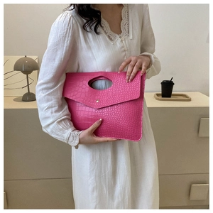 Detail of hot pink crocodile embossed envelope clutch bag with oval handle cut-out