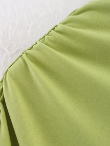 Dettaglio ravvicinato del tessuto verde arricciato e della trama in maglia del top