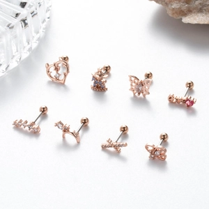 Detailed macro view of rose gold surgical steel cartilage studs with heart and butterfly designs