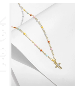 Detail of gold cross pendant with clear zircon and colorful enamel beads on dainty chain