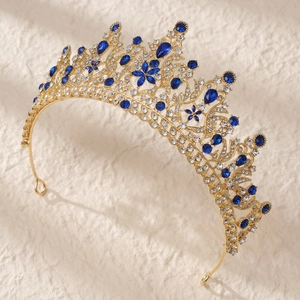 Luxurious gold crown with blue teardrop gemstones and white crystals on beige background