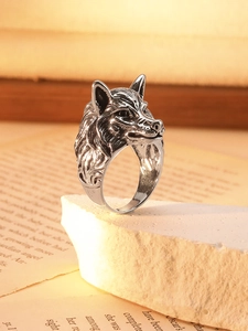 Macro shot of vintage silver wolf head ring with detailed engraving on stone background