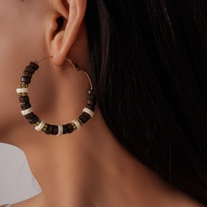 Detail of bohemian hoop earrings with dark wood beads and cream accents on a model