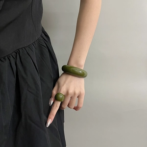 Close-up of olive green resin jewelry set featuring a wide bangle and an oval dome ring