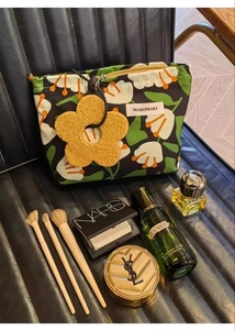 Detail of tropical canvas makeup bag featuring floral prints and yellow flower charm