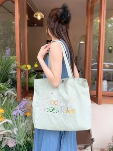 Sac fourre-tout en toile vert clair avec broderie Lucky Zakka porté par un mannequin