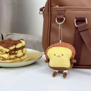 Mini plush toast keychain with sad expression hanging on a bag, cute bread pendant