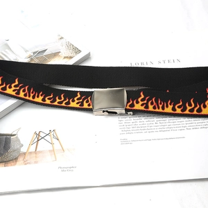 Detail of black canvas belt featuring vibrant flame print and silver metal buckle