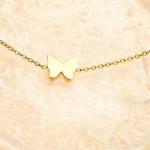 Elegant gold butterfly pendant necklace for women on a textured ripple water background