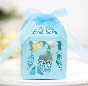 Close-up of light blue laser-cut heart wedding favor box with thank you text and ribbon