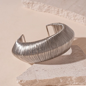 Detailed view of silver woven wire cuff bracelet on stone, minimalist jewelry photography