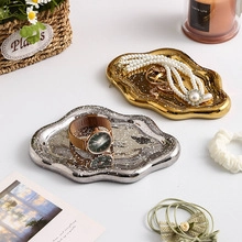 Close-up of gold and silver ceramic jewelry trays with unique meteorite texture and pearls