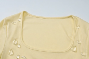 Dettaglio del top in maglia a costine con scollo a U e ciondolo a goccia d'acqua trasparente