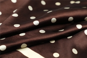 Close-up of brown polka dot satin fabric showing smooth texture and silky glossy finish