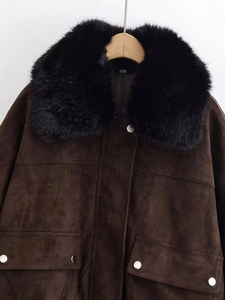 Detail of a dark brown faux suede jacket featuring a plush black faux fur collar and metal buttons