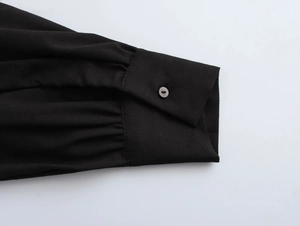 Detail of elegant black pleated sleeve cuff with functional button and fabric texture