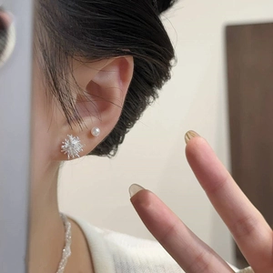 Silver starburst and pearl stud earrings set shown on ear for a minimalist jewelry look