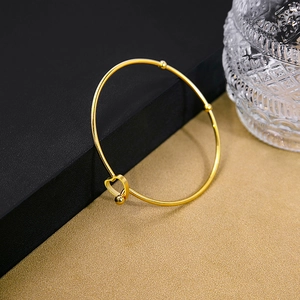 Macro shot of gold heart buckle on minimalist metal bangle with elegant polished finish