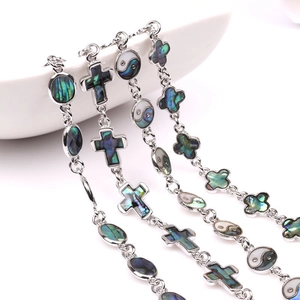 Detail view of silver bracelets with abalone shell heart and cross charms