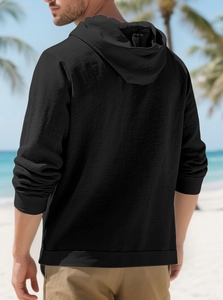 Detail of black hooded linen shirt fabric texture on a model at a beach resort