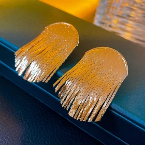 Macro shot of golden fringe earrings with dense metal chains on a jewelry box