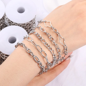 Various silver stainless steel DIY jewelry chains wrapped around a wrist with a metal spool