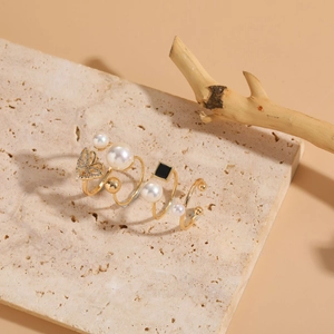 Detailansicht eines vierteiligen Goldring-Sets mit Perlen, Zirkonia-Schmetterling und Akzenten